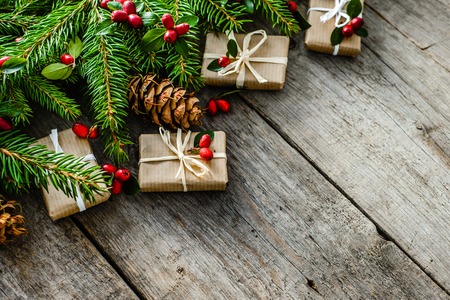 Wooden background with christmas decorations, red ornaments and christmas gift boxes on green branches of fir, festive border with copy spaceの写真素材