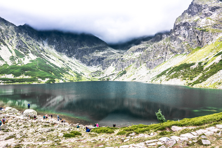 ZAKOPANE, POLAND - AUGUST 16, 2016: Group of hikers over lake in mountains, travel destination of tourist trip in the summer, Czarny Staw Gasienicowy, High Tatra Mountainsのeditorial素材