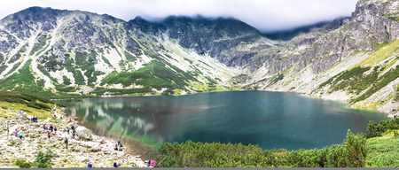 ZAKOPANE, POLAND - AUGUST 16, 2016: Group of hikers over lake in mountains, travel destination of tourist trip in the summer, Czarny Staw Gasienicowy, High Tatra Mountainsのeditorial素材