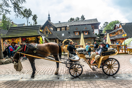 ZAKOPANE, POLAND - AUGUST 17, 2016: Touristic season in Zakopane, tourist recreation on the Krupowki street. Carriage with coachman and harnessed horseのeditorial素材