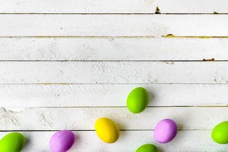 Spring easter eggs background, seasonal colored eggs on white wooden boardsの写真素材