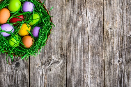 Spring easter eggs, background with colored eggs in nest on wooden tableの写真素材