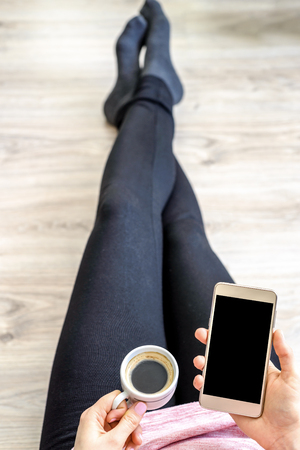 Person with smart phone and coffee, smartphone with black screen, people using internet and wifi technologyの写真素材