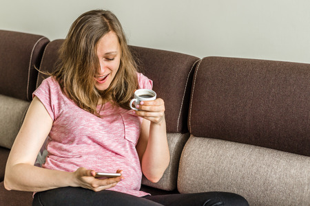 Happy woman drinking coffee and using mobile phone in hand, modern lifestyle conceptの写真素材