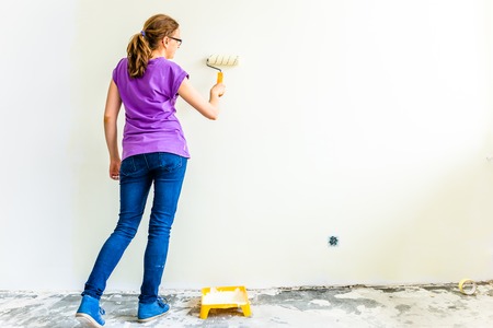 Painting wall using paint brush, working indoors, home renovation conceptの写真素材