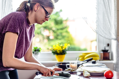 Woman in the kitchen, cooking vegetable salad for tortilla with chicken and kebab gyros fillingの写真素材