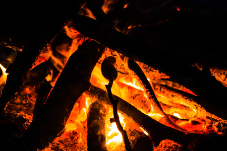 Roasted sausage over bonfire, barbecue with sausages, outdoor picnic with summer camp fire.