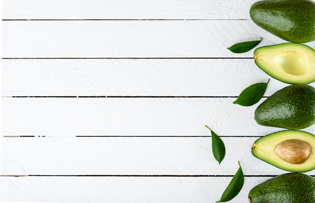 Fresh avocados on wooden table, fresh whole and halves of avocado, top viewの写真素材