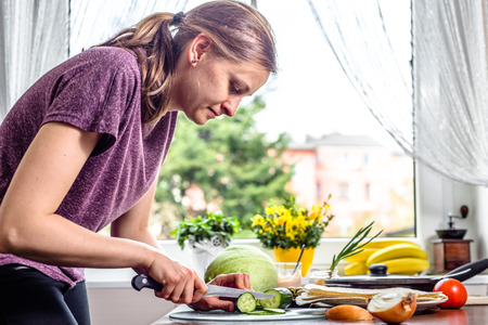Woman in the kitchen, cooking vegetable salad for tortilla with chicken and kebab gyros fillingの写真素材
