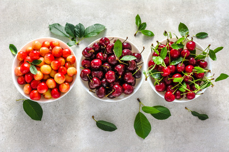 Different cherry on plate on white background, ripe cherries, sweet fruit, top view