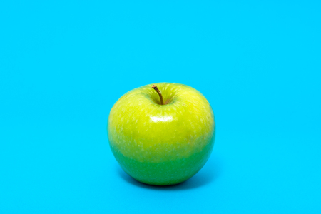 Single green fresh apple on blue backgroundの写真素材