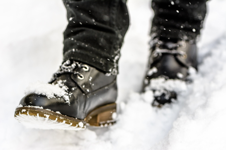 Black boots in snow, person put the step in snow, walking in winterの写真素材