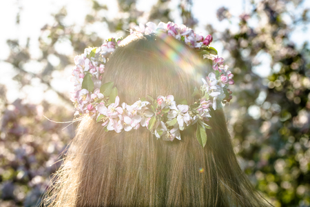 Blonde woman with a wreath of flowers in hair, back viewの写真素材