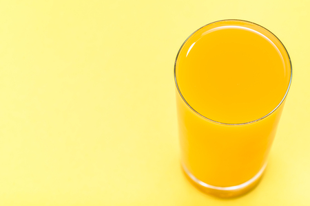 Fresh juice in a glass. Orange juice on yellow backgroundの写真素材