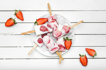Natural juicy strawberry popsicles with yogurt. Refreshing ice pops, overhead, flat layの写真素材