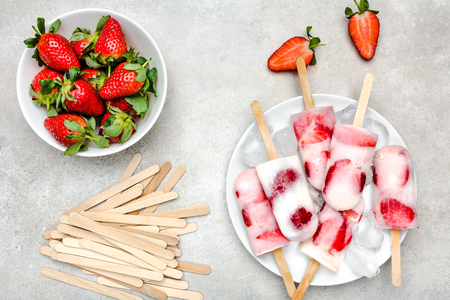 Natural juicy strawberry popsicles with yogurt. Refreshing ice pops, overhead, flat layの写真素材