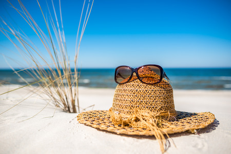 Hat and sunglasses. Accessories for sun protection on the sea beach, summer holiday vacation over Baltic, Polandの写真素材