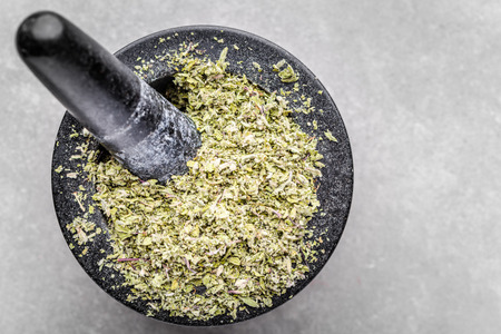 Herbal tea or dry herb in mortar, top view of aromatic spice - dried oregano, basil, marjoram or parsley - crushed leaves in mortarの写真素材