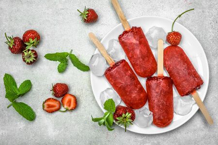 Natural juicy strawberry popsicle with fruits. Red popsicles on plate.の写真素材