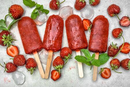 Homemade popsicles with fruits. Strawberry ice lollies on sticks, top view, flat layの写真素材