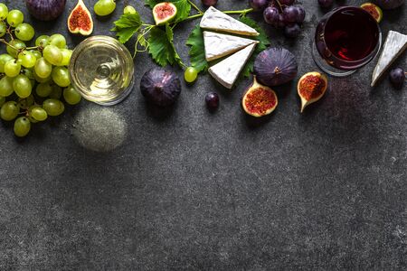 Glasses of red and white wine with cheese, grapes and figsの写真素材