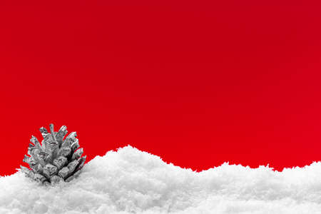 Christmas red background with snow and christmas pine coneの写真素材