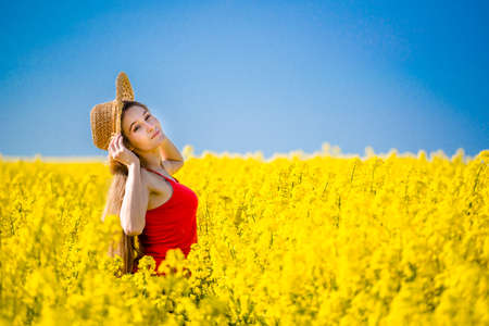 Summer portrait of woman in rapeseed. Rural scene with model girl enjoying sun in yellow flowers in field. Concept of joy, happiness and freedom.の写真素材
