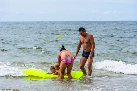 LEBA, POLAND - JULY 31, 2016: Young family having fun in sea water, kids swimming on mattress, tourists enjoying in summer holiday seasonのeditorial素材