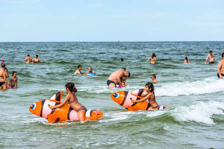 LEBA, POLAND - JULY 31, 2016: Group of tourists, adults and kids playing and swimming in sea water, happy people enjoying on the beach in summer holiday seasonのeditorial素材