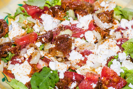 Salad with vegetables with feta cheese and sun-dried tomatoes, macro close-up, food backgroundsの写真素材