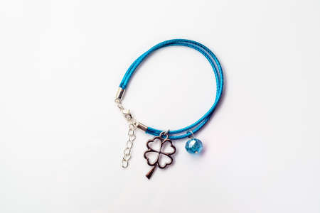 Close-up of fashionable bracelet made with blue leather, clover pendant and crystal glass isolated on white background, top view.の写真素材