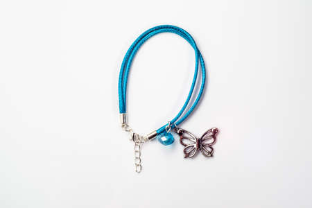 Close-up of handmade bracelet made with blue leather straps, crystal glass and butterfly pendant isolated on white background, top view.の写真素材