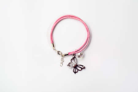 Close-up of handmade bracelet made with pink leather, crystal glass and butterfly pendant isolated on white background, top view.の写真素材