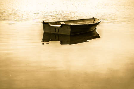 Vintage photo of old boat for fishing on the lake, quiet surface of water. Nature background, vintage effect.の写真素材