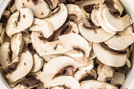 Background with mushrooms champignon sliced and arranged in pot, vegetarian food close-up.の写真素材