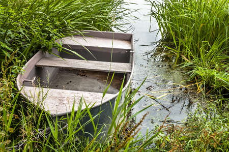 Boat for fishing on the lake at the shore among the reeds. Outdoor wedding theme. Theme of vacation, holiday, leisure and relaxation.の写真素材
