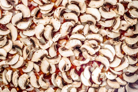 Mushrooms champignon sliced and arranged on pizza margherita for background or texture, top view, fast food preparation close-up.の写真素材