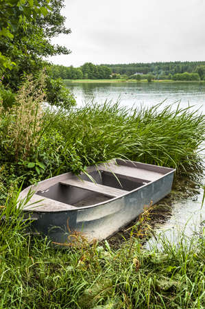 Boat for fishing on the lake at the shore among the reeds. Outdoor wedding theme. Theme of vacation, holiday, leisure and relaxation.の写真素材