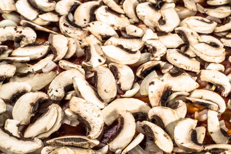Preparation of pizza margherita with mushrooms champignons sliced for background or texture, shallow depth of field, fast food close-up.の写真素材