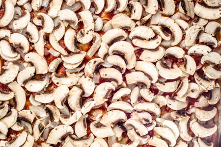 Mushrooms champignon sliced and arranged on pizza margherita for background or texture, top view, fast food preparation close-up.の写真素材