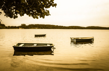 Landscape stylized on vintage with boats for fishing on the lake at the shore. Vintage photo. Nature background. Tranquil landscape.の写真素材