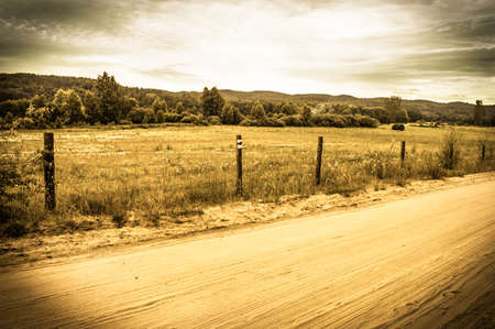 Landscape stylized on vintage with rural scene, rural road, fields and meadows at summer. Idyllic rural landscape and agricultural with vintage vignette effect.の写真素材