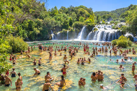 KRKA NATIONAL PARK, CROATIA - AUG 19, 2019: People swim in river over Skradinski Buk waterfall in Croatia, tourism and vacation travel destination.のeditorial素材