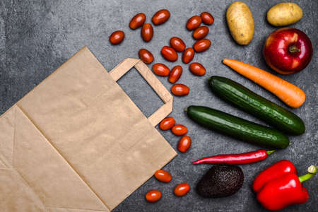 Healthy food background. Delivery of healthy vegetarian food in bag. Vegetables and fruits on black stone. Shopping food in supermarket. Clean vegetarian eating concept.の写真素材