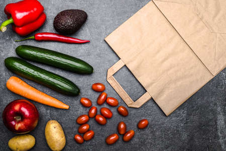 Healthy food background. Delivery of healthy vegetarian food in bag. Vegetables and fruits on black stone. Shopping food in supermarket. Clean vegetarian eating concept.の写真素材