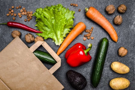Healthy food background. Delivery of healthy vegetarian food in bag. Vegetables and fruits on black stone. Shopping food in supermarket. Clean vegetarian eating concept.の写真素材