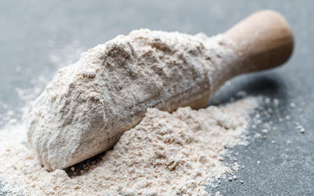 Spelt flour in wooden spoon on dark backgroundの写真素材