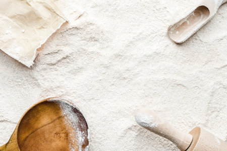 Background with flour. Rolling pin, wooden spoon, paper bag and flour, flat lay, top view.の写真素材