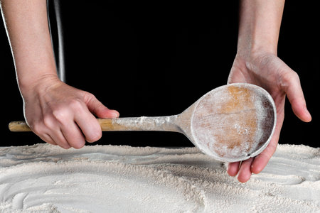 Baker with wooden spoon above flour. Baking concept.の写真素材
