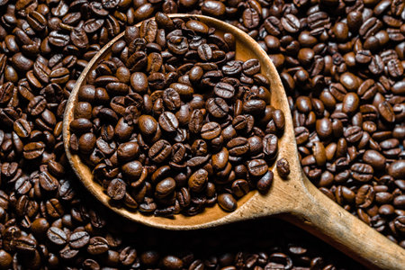 Freshly roasted coffee beans in wooden scoop. Black coffee background.の写真素材